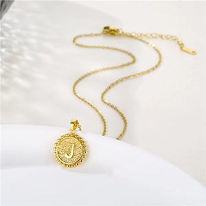 Detailed view of golden initial J necklace featuring a round beaded pendant and chain