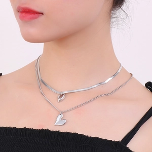 Detail of silver double layer necklace featuring flat snake chain and heart pendant on model
