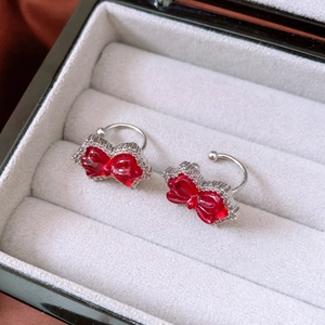 Close-up of sparkling red bow ear cuff with silver frame and diamonds in a jewelry box