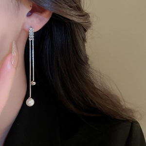 Close-up of model wearing long silver tassel earrings with zircon and pearl accents
