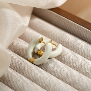 Close-up of gold hoop earrings with white enamel on a beige jewelry storage box
