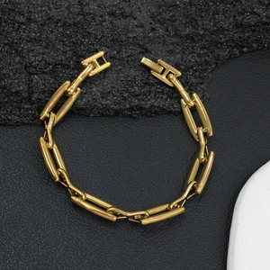 Nahaufnahme eines goldenen Gliederkettenarmbands auf dunklem Steinhintergrund