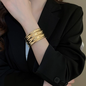 Detail of a gold wavy metal cuff bracelet with a wrinkled texture and mirror finish
