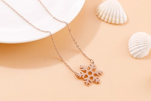 Close-up of snowflake pendant necklace in rose gold finish on minimalist background