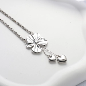 Macro shot of silver floral pendant and heart charms on a sleek box chain necklace