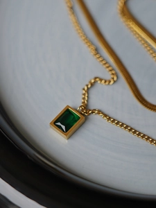Detail of emerald green zircon pendant on double-layered gold snake chain necklace