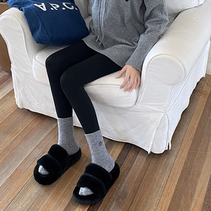 Close-up of thick ribbed knit socks paired with black faux fur slippers for winter warmth