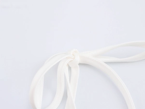 Detail der weißen Satinschlaufe mit elegantem Knoten für ein stilvolles Oberteil