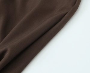 Macro shot of dark coffee twill fabric detail showing smooth texture and drape