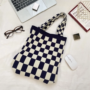 Gros plan de la texture du sac cabas tricoté à damier sur un bureau avec accessoires