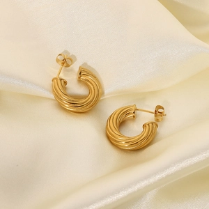 Detailed view of 18K gold plated twisted hoop earrings on beige silk fabric background
