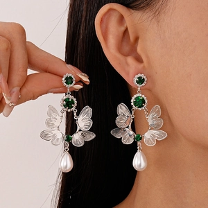 Vintage silver butterfly earrings with green stones and pearl droplets on a model