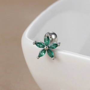 Macro shot of green zircon daisy flower stud earring on a white ceramic rim