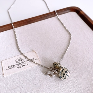 Detailed close-up of a silver pony pendant and spotted stone beads on a dainty bead chain