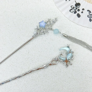 Detailed close-up of moon and star hairpins with silver tassels and light blue moonstones