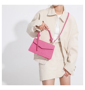 Detail of pink woven PU leather crossbody bag with knot strap and gold metal hardware