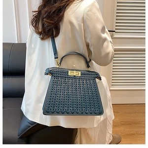 Close-up of the woven texture and golden twist lock on this dark blue designer handbag