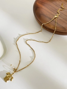 Detailed close-up of golden turtle pendant necklace with a small white pearl accent