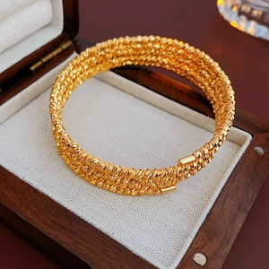 Detail of multi-layered gold plated spiral bracelet with sparkling textured surface in box