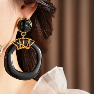 Gros plan de boucles d'oreilles géométriques en résine vintage portées par un mannequin