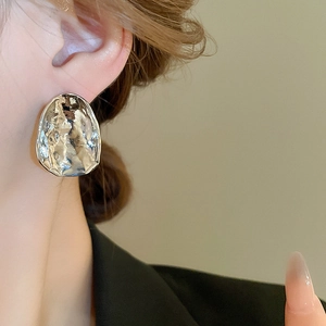 Detail of silver irregular metal stud earrings with lava texture on a female model