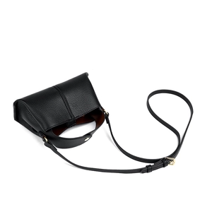 Macro shot of black leather trapezoid handbag with gold hardware and brown lining interior