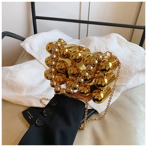 Detail of gold egg-shaped acrylic evening bag with pearl handle and metal sphere texture