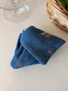 Détail de la pince à cheveux en denim bleu avec broderie de cerises et de cœurs rouges