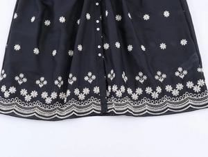 Close-up of white floral embroidery and buttons on black puff sleeve v-neck dress