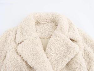 Detail shot showing the fluffy texture and collar design of the off-white faux fur teddy coat