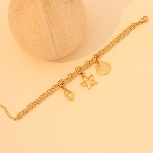 Gold layered stainless steel necklace with starfish and seashell pendants on stone stand