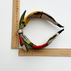 Detail view of colorful satin knotted headband width measurement with a wooden ruler