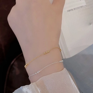Detail of minimalist S925 silver beaded bracelets in gold and silver on a woman's wrist