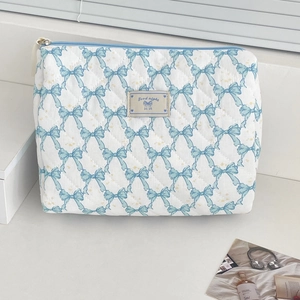 Macro view of white quilted cosmetic bag with blue bows and high quality cotton texture