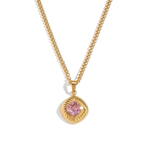 Macro shot of gold necklace with pink diamond-shaped zircon pendant and textured metal lace