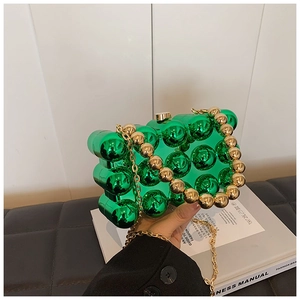 Detail of green acrylic beaded handbag featuring a stylish gold chain shoulder strap