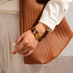 Detail of amber resin beaded bracelet with gold metal edges against a woven bag background