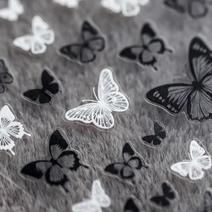 Delicate 5D butterfly nail stickers in black and white with 3D texture on gray fur background