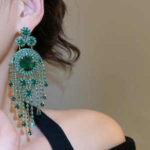 Close-up of elegant emerald green tassel earrings on model showing sophisticated luxury style