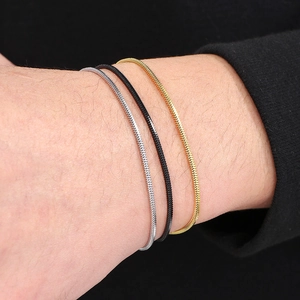 Close-up of minimalist silver, black and gold snake chain bracelets on a male wrist