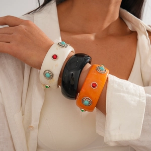 Close-up of vintage resin bangles with acrylic marble patterns and inset gemstones