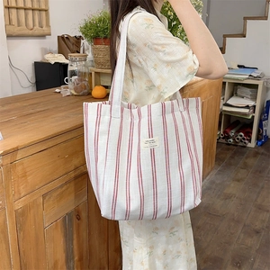 Detailed close-up of red striped canvas tote bag with woven sunshine label and shoulder strap