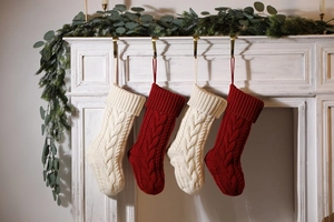 Close-up of four red and white cable knit Christmas stockings hanging on a white mantel