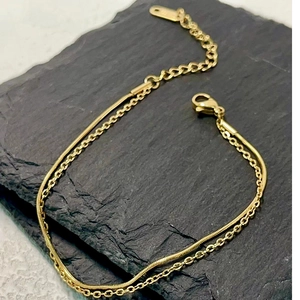 Double-layer 18k gold-plated snake and cable chain bracelet on dark stone background