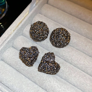 Détail macro de boucles d'oreilles cœur et rondes avec strass noirs micro-paves