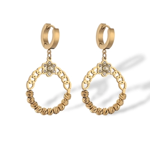 Gros plan de boucles d'oreilles dorées géométriques avec fleurs et détails en zircon