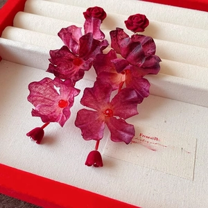 Dettaglio macro di orecchini a rosa rossa in tessuto con petali di seta pregiata