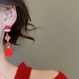 Detail of red tassel earrings with gold Chinese character plaque and mascot charm