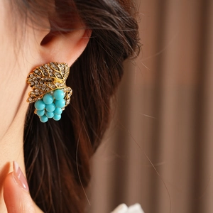 Detailed close-up of vintage gold leaf earrings with rhinestones and blue beads