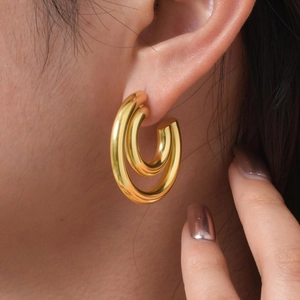 Macro view of minimalist 18K gold double hoop C-shaped earrings worn on model